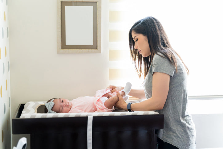 Mother changing her baby's diaper on a changing table