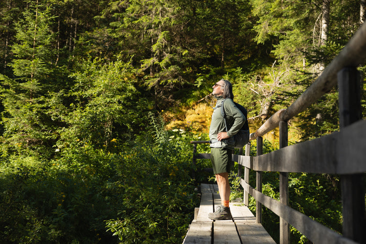 Hiker pausing on a wooden boardwalk trail in a green forest