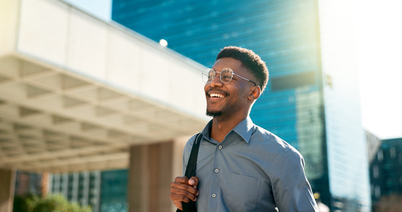 Smiling man with a backpack walking past an office building