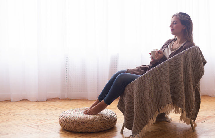 Woman relaxing in an armchair with a blanket and a warm drink