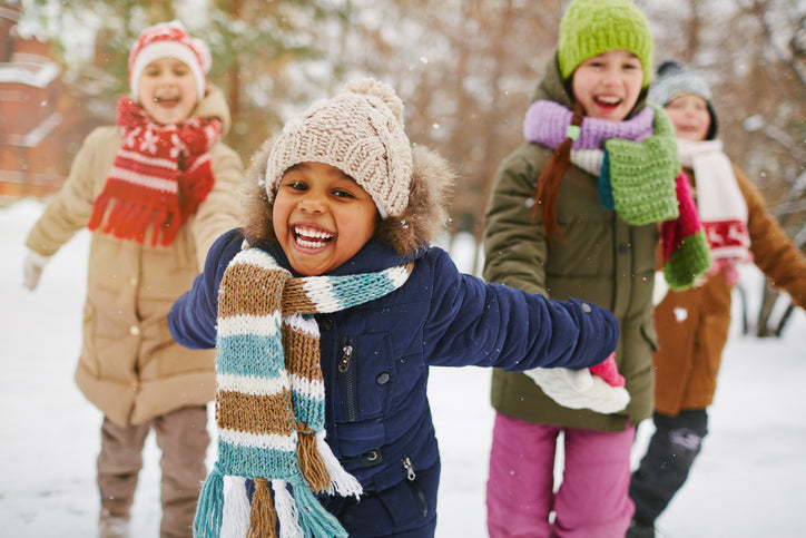 Laughing kids in hats and scarves playing in the snow