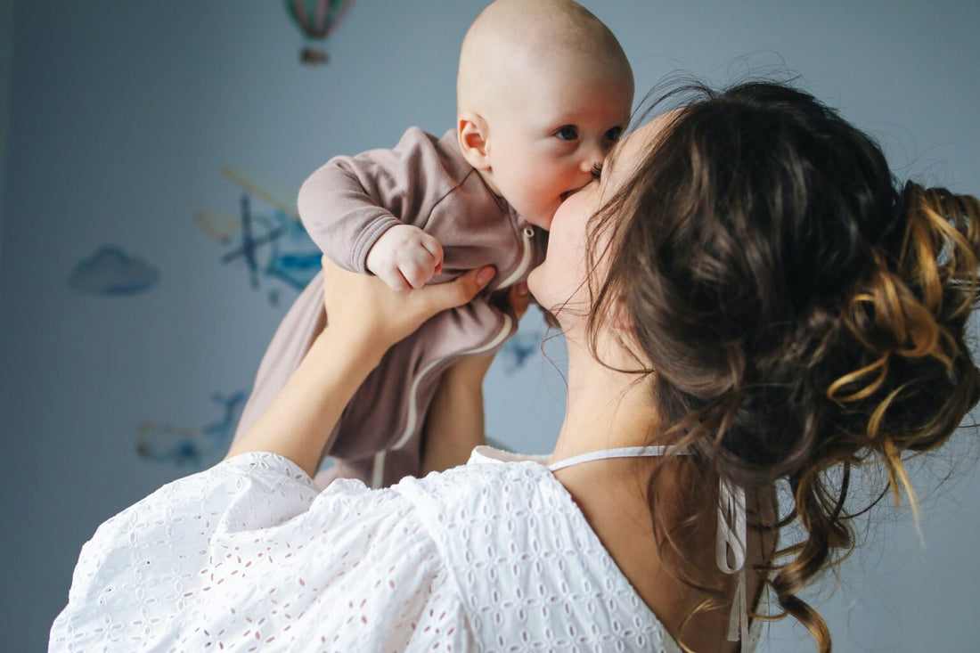 Mother lifting her baby up and kissing her cheek
