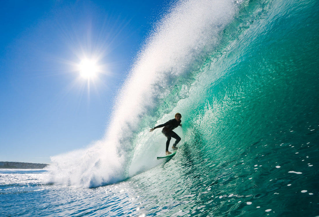 Surfer riding inside a curling turquoise wave on a sunny day