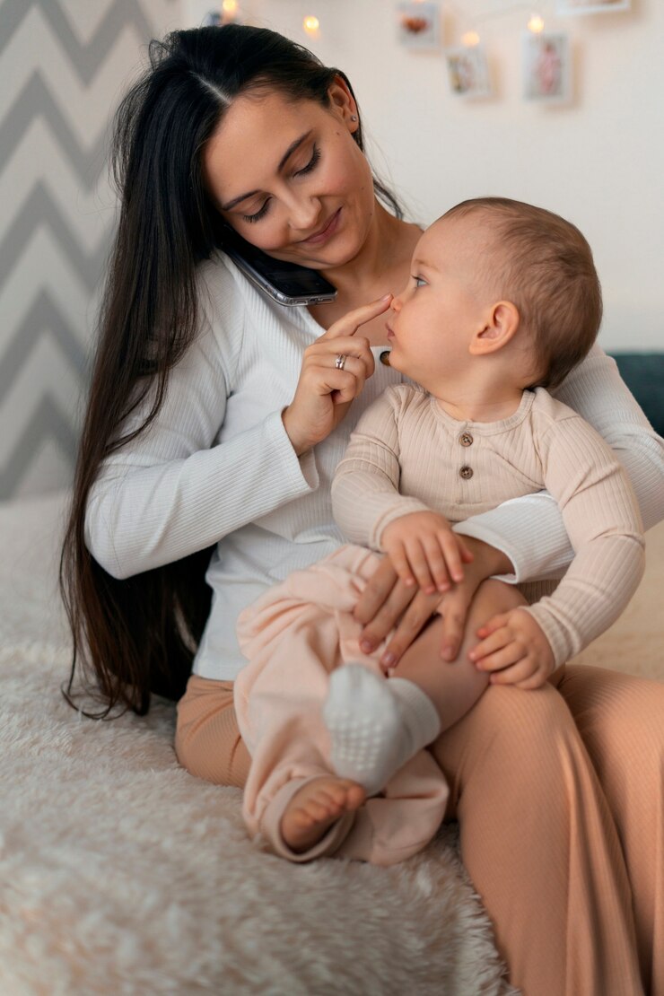 Mother sitting on a bed holding her smiling toddler on her lap